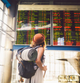 Junge Frau liest Anzeigetafel am Flughafen.